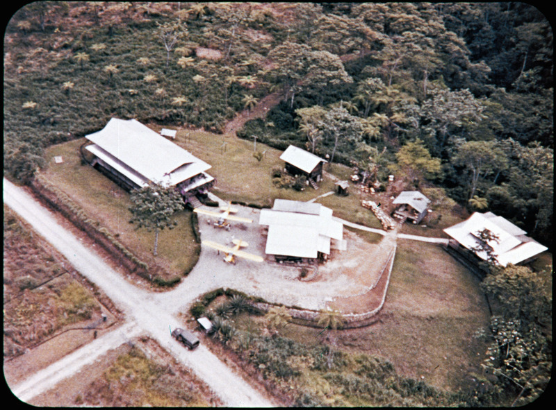 Photograph of the MAF base at Shell Mera from above, including part of the airstrip and the home of Nate and Marj Saint. Image used in filmstrip <i>Unforgettable Friday</i>, which tells the story of Nate Saint and his family, missionary work with Mission Aviation Fellowship and involvement in Operation Auca. Filmstrip was developed by Marj Saint and MAF in late 1956.