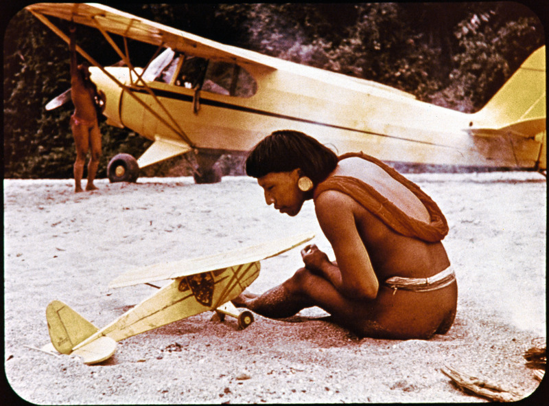 Naenkiwi inspects model of Nate Saint's plane during visit to five missionaries at Palm Beach, January 6, 1956. One frame from filmstrip titled "Unforgettable Friday," which tells the story of Nate Saint and his family, missionary work with Mission Aviation Fellowship and involvement in Operation Auca. Filmstrip was developed by Marj Saint and MAF around 1956.