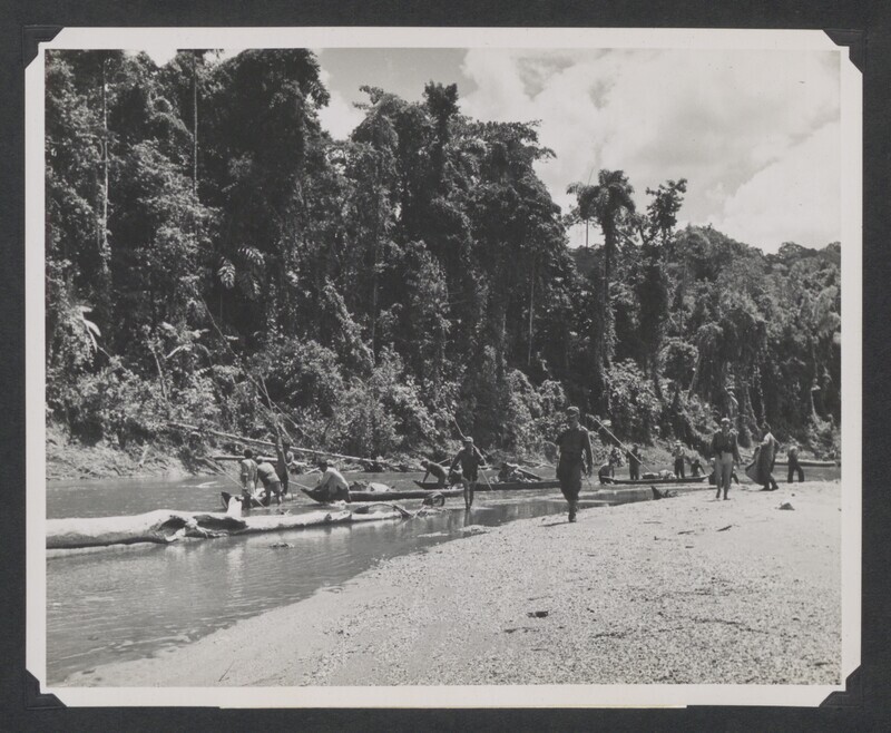 Team of Ecuadorian soldiers, Quichua Indians, and missionaries conduct ground search for missionaries by canoe down Curaray River. Original USCARIB Central caption reads: "Ground party personnel, consisting of Ecuadorian soldiers, American missionaries, and friendly Indians, search along the banks of the Curaray River in the upper Amazon basin of Ecuador for the bodies of the five American missionaries murdered by savage Auca Indians. Four of the bodies were subsequently recovered and buried in a common grave beneath the tree house they had constructed alongside the sandy beach where they were murdered."