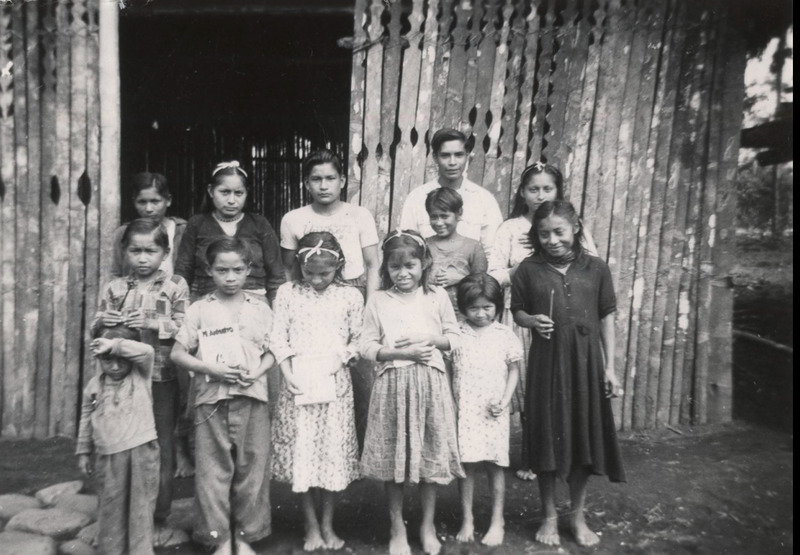 Photograph of Quichua children at school in Puyupungu. Caption from Jim Elliot: "Our School Gang in Puyupungu. 2nd row 2nd from left is the girl we married this morning. Beside her is the boy who arrived for baptism and beside him is our believing teacher Lucas."  Black and white photograph, 1.5x2.5 in.