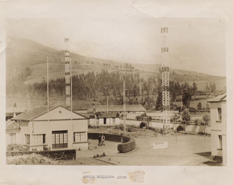 The HCJB office and radio towers, c. 1930-1940. In Spanish, the call letters meant “Hoy Christo Jesus Bendice” (Today Jesus Christ Blesses) and in English “Heralding Christ Jesus’ Blessings.”  Opened in Quito in 1931 by Clarence Jones and Reuben Larson, the station and its parent organization, World Radio Missionary Fellowship (later renamed to Reach Beyond), soon became one of the major Protestant institutions in Ecuador, a supporter of both missionary efforts and the indigenous Evangelical churches. 