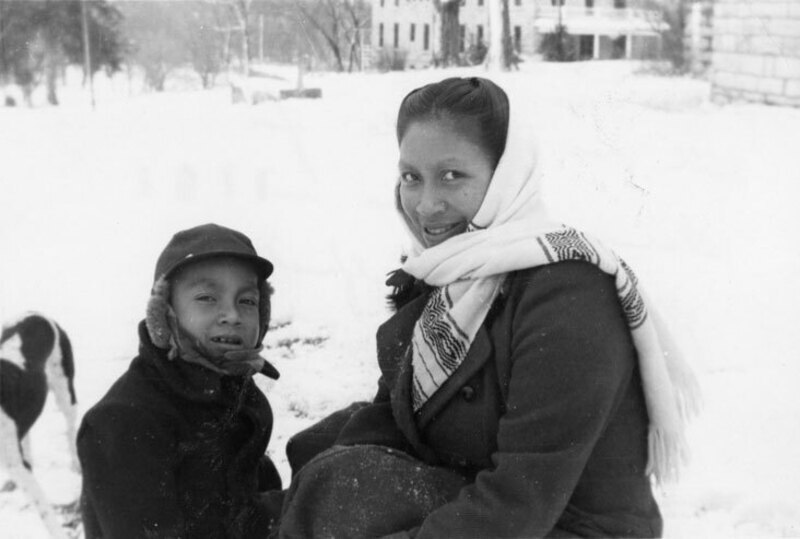 Photograph of Dayuma and her son Ignacio (Sam) wearing coats in a snowy landscape at the SIL retreat in Sulphur Springs, Arkansas. Photo has caption: "For Dr. and Mrs. Edman with our gratitude for sharing with us in offering the first fruits to Him who loved the Aucas and gave Himself for them. Rachel, Dayuma, and Ignacio."