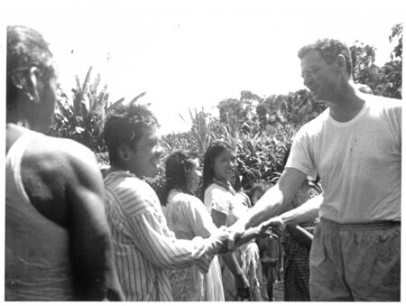 Yowe shakes hands with Dr. Everett Fuller after his baptism. From Caption: "Auca Baptisms. Dr. Everett Fuller of HCJB gives the hand of Fellowship to Dywui [Yowe], center, Gimari [Guiimadi] (Delilah) of the Palm Beach. Right - Oba - both of whom are Dayuma's sisters."